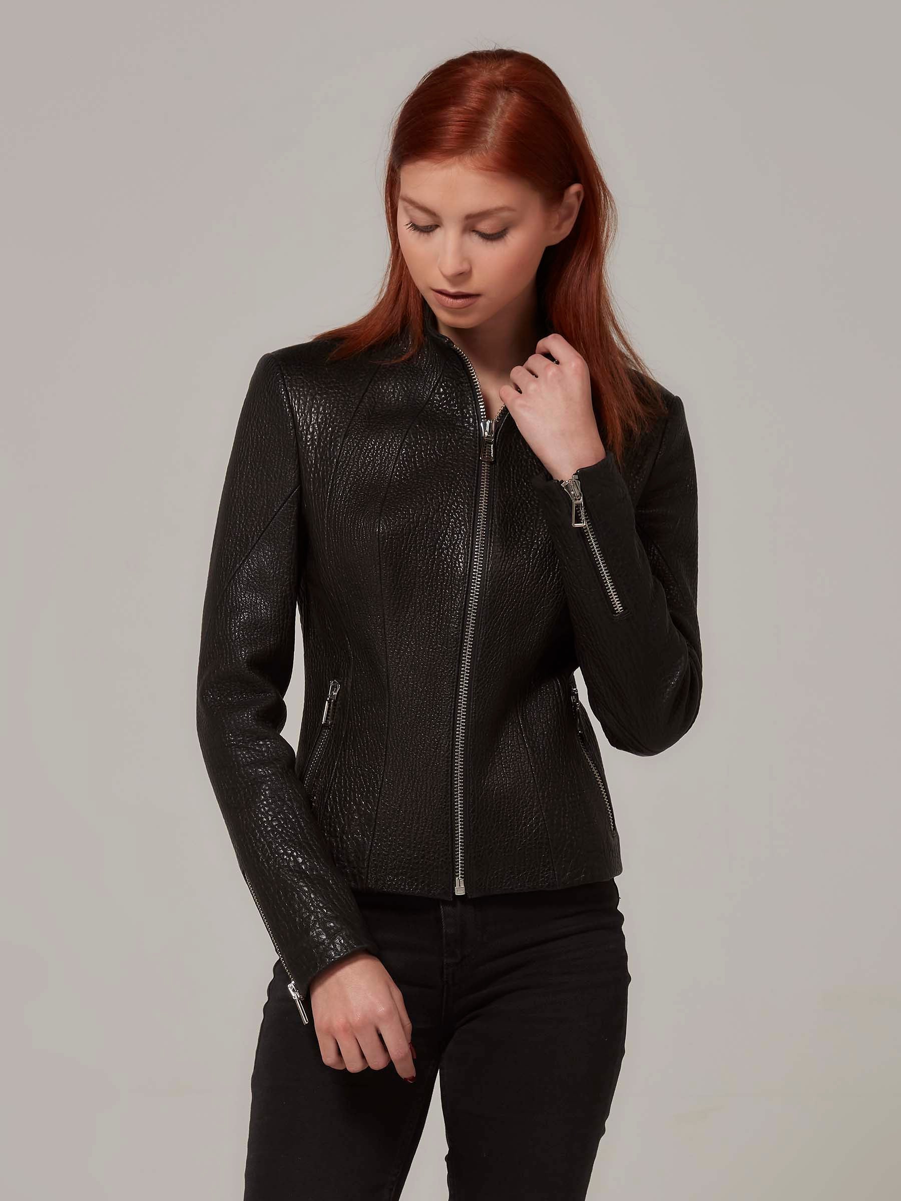 Black leather biker jacket with a distinctive texture, worn by a woman with red hair,standing.