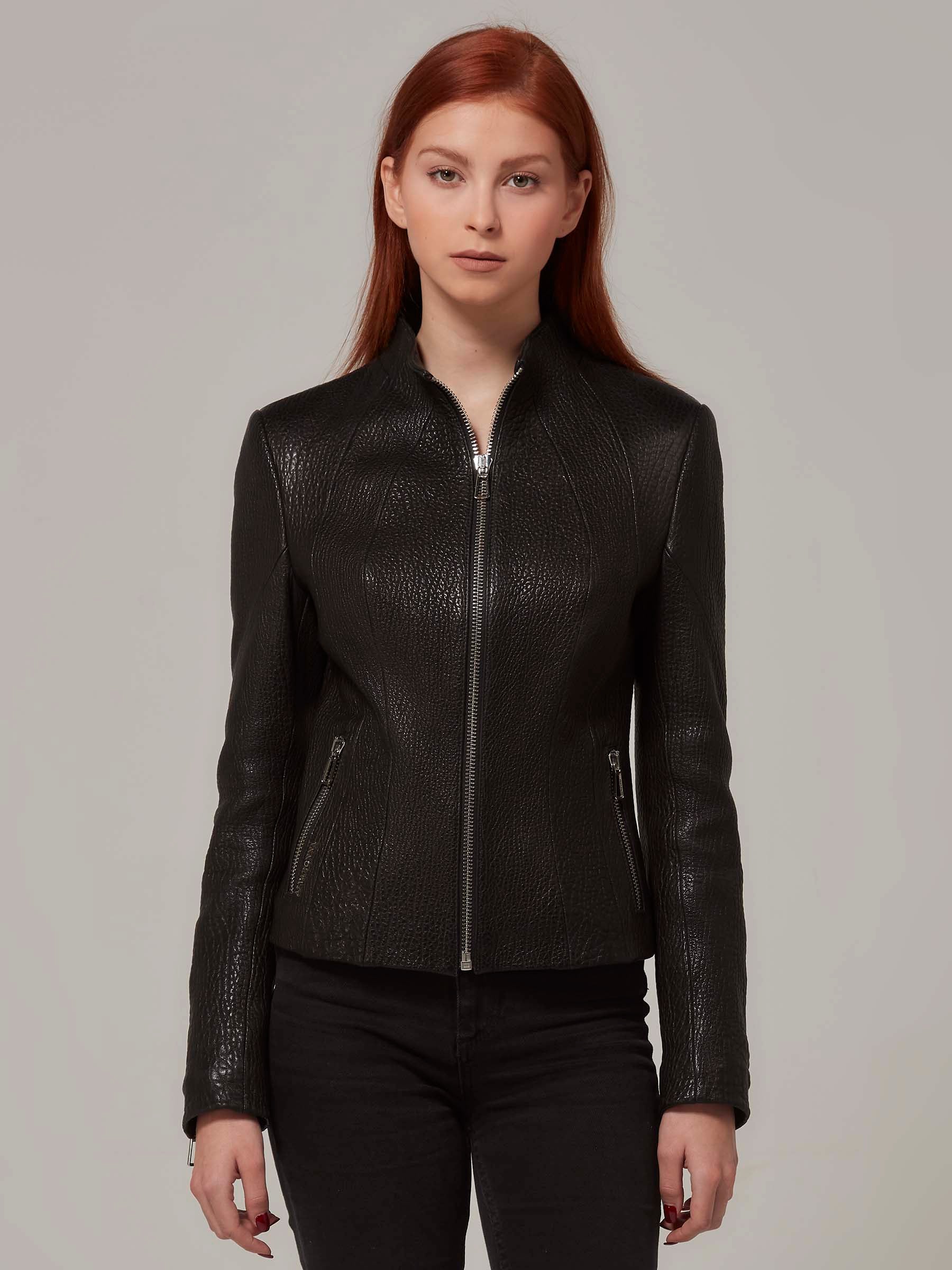 Close-up front view of a black leather biker jacket with a distinctive texture, worn by a redheaded woman.