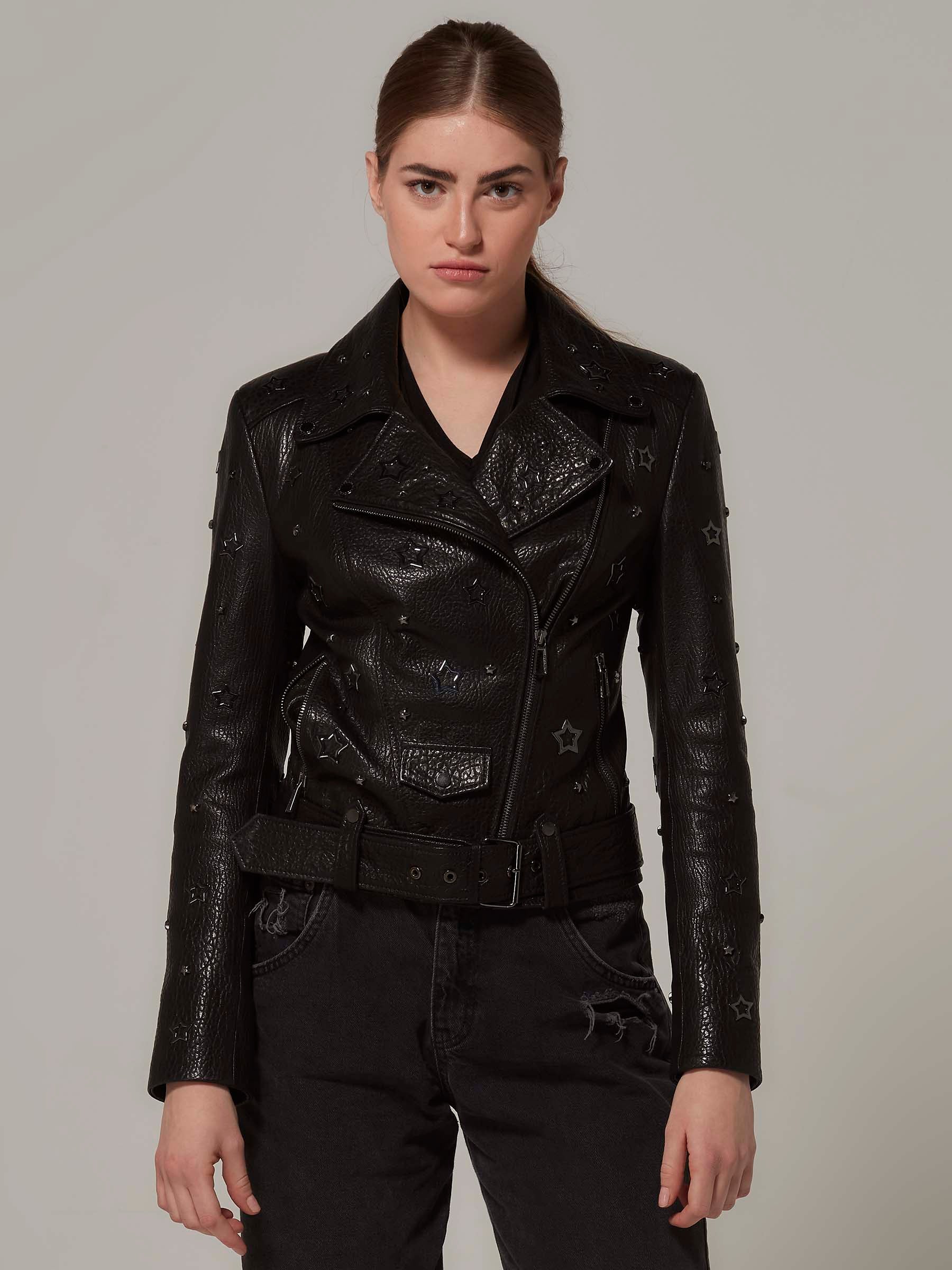 Woman in a black,  biker jacket adorned with star details, with the unique texture of the leather and embodying a rebellious rock attitude. Standing front view pose.