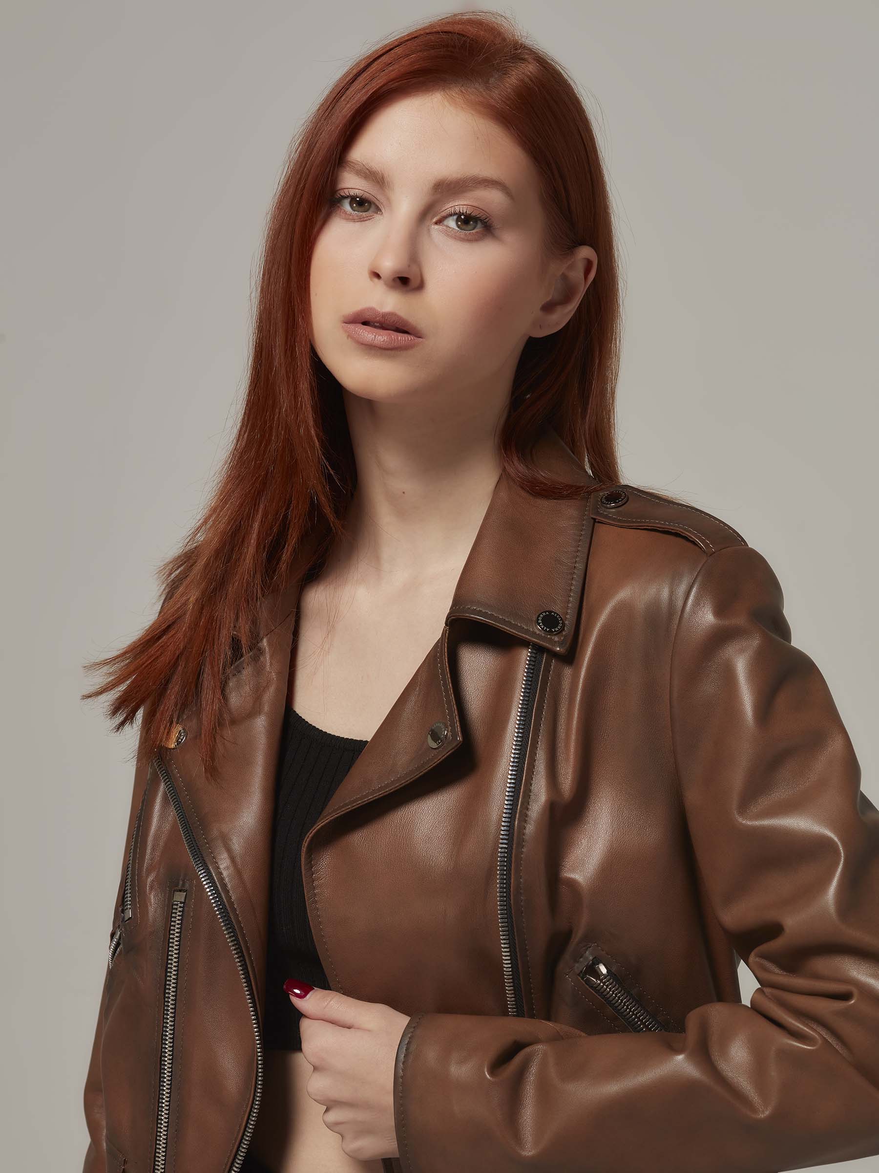 Woman in vintage brown leather biker jacket, motorcycle jacket, moto style,  standing. (close up)