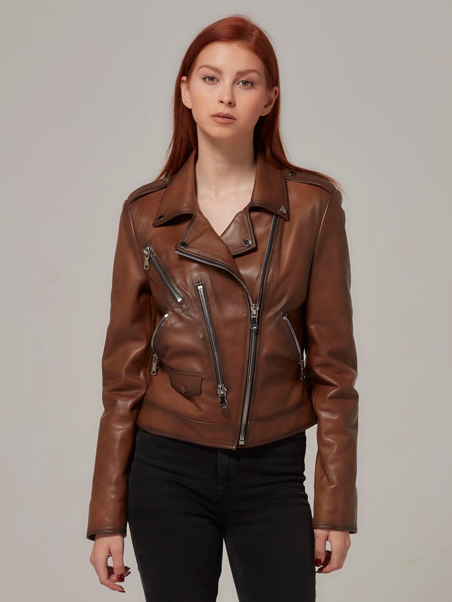 Woman in vintage brown leather biker jacket, motorcycle jacket, moto style, standing.